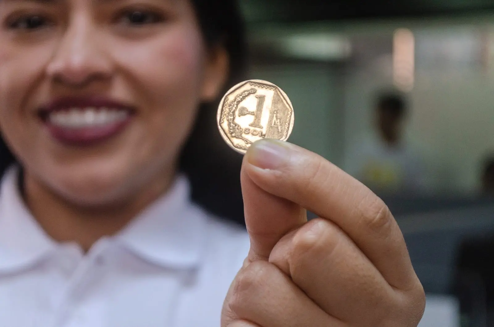 Una alumna muestra una moneda de un sol